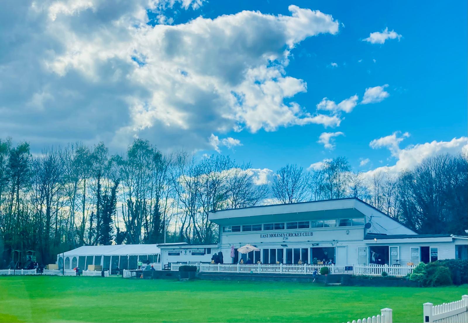 The East Molesey Cricket Club clubhouse on a bright day with blue skies over the ground