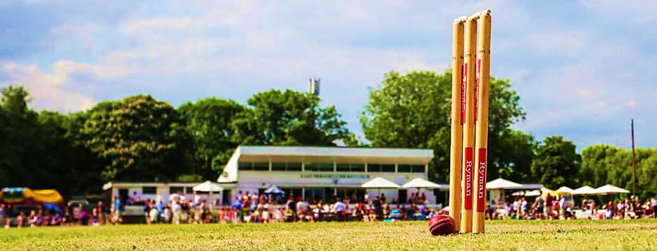 Cricket stumps on the outfield with the East Molesey pavilion beyond