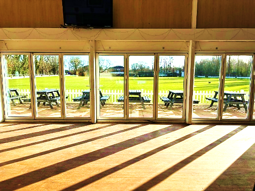 Sunlit view of the ground through the clubhouse doors