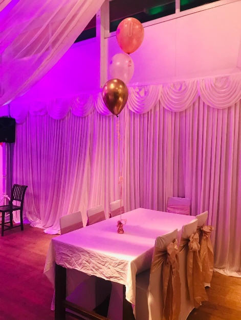 Celebration table framed by soft pink draping and balloons