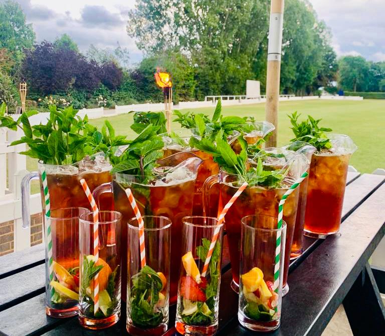 Jugs and glasses of Pimm's on a terrace table beside the pitch