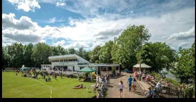 The clubhouse and riverside ground busy with families on a sunny summer's day