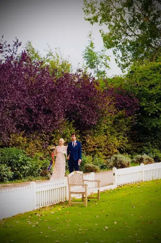 Wedding couple posing beside the white boundary fence